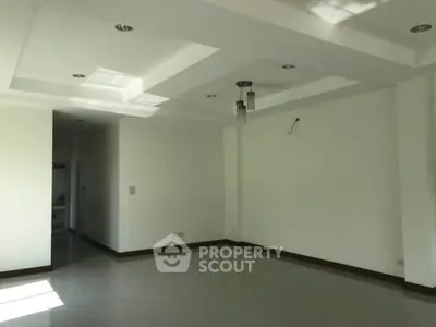 Spacious empty living room with modern ceiling design and ample natural light.