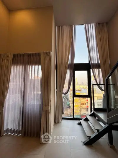 Stunning high-ceiling room with floor-to-ceiling windows offering a breathtaking city view.