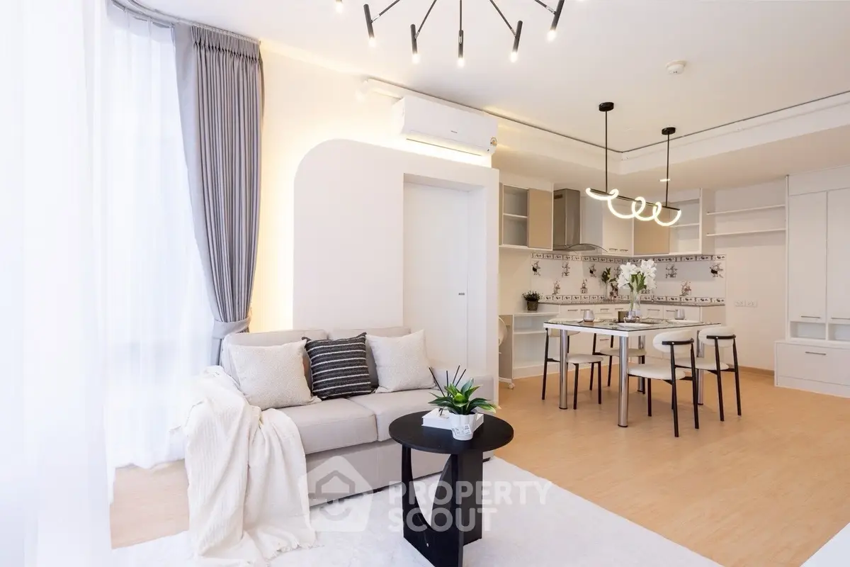 Modern open-plan living room with stylish decor and dining area, featuring elegant lighting and cozy ambiance.