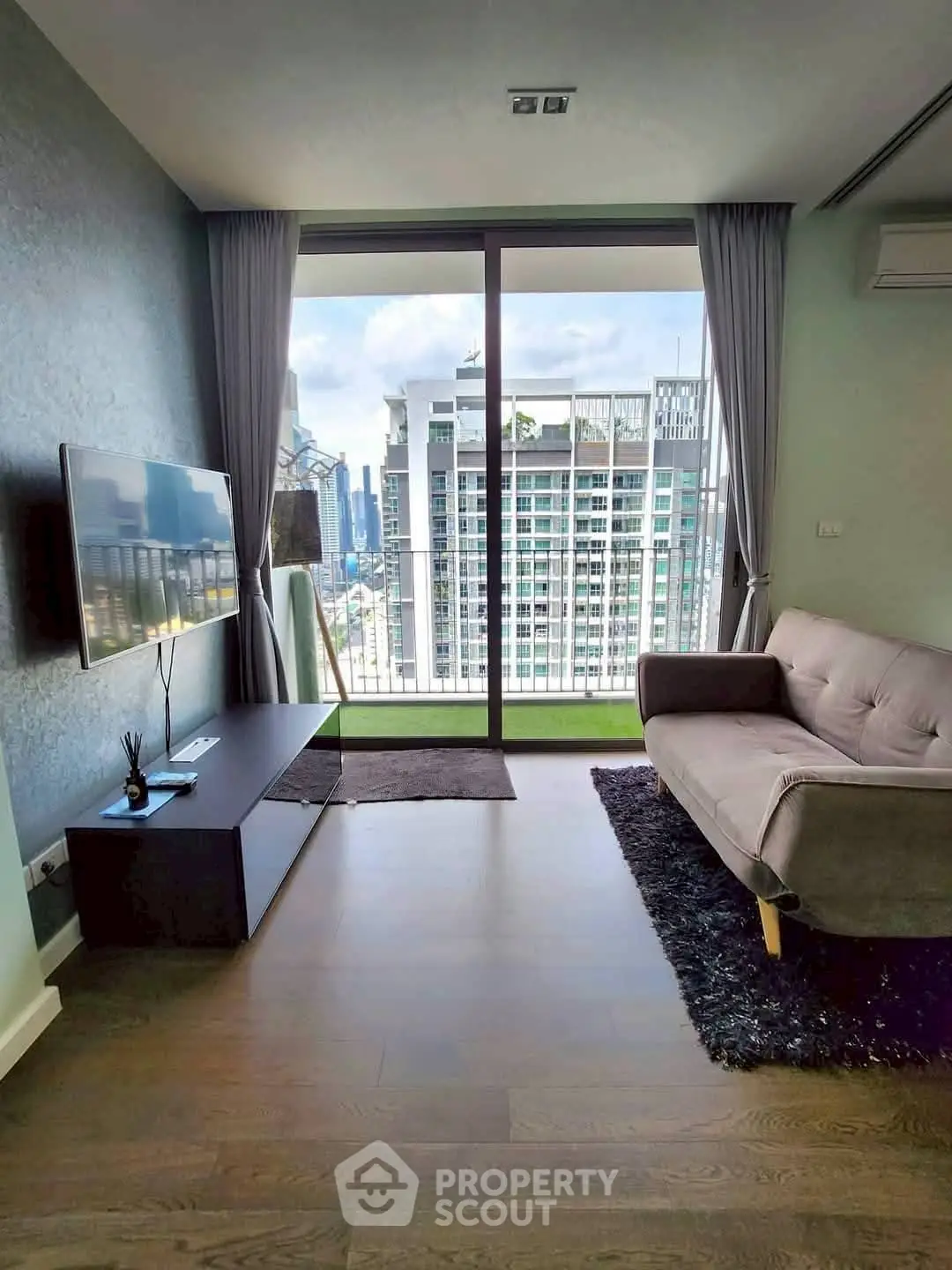 Modern living room with city view, featuring sleek furniture and floor-to-ceiling windows.