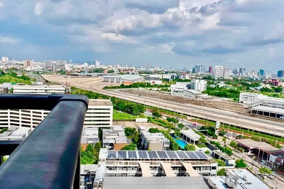Stunning cityscape view from high-rise balcony overlooking urban skyline and railway tracks.