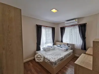 Cozy bedroom with wooden flooring, large windows, and air conditioning in modern apartment.
