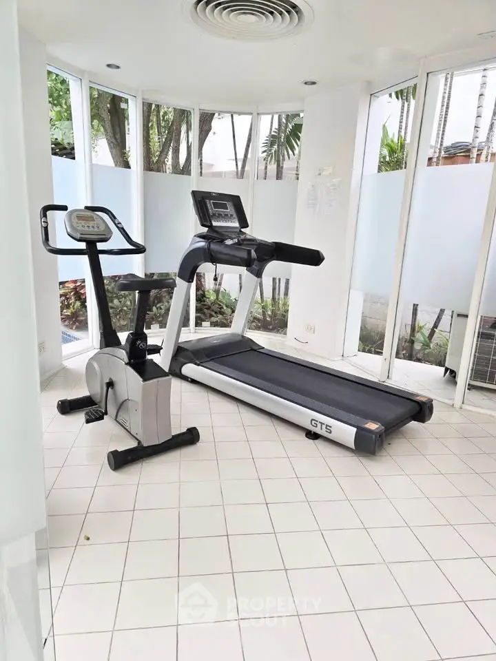 Modern gym with treadmill and exercise bike in bright, airy space.