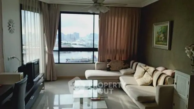 Spacious living room with large window offering stunning city and water views.