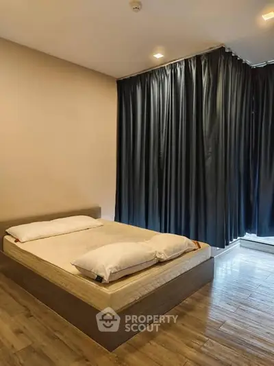 Modern bedroom with wooden flooring and dark curtains