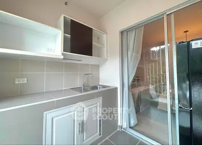 Modern kitchen with sleek cabinetry and sliding glass door leading to a cozy balcony.