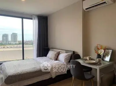 Modern bedroom with city view, featuring cozy bed and stylish dining area.