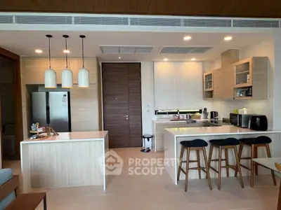 Modern kitchen with island, bar stools, and sleek appliances in open layout.