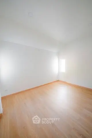Spacious empty room with wooden flooring and bright natural light
