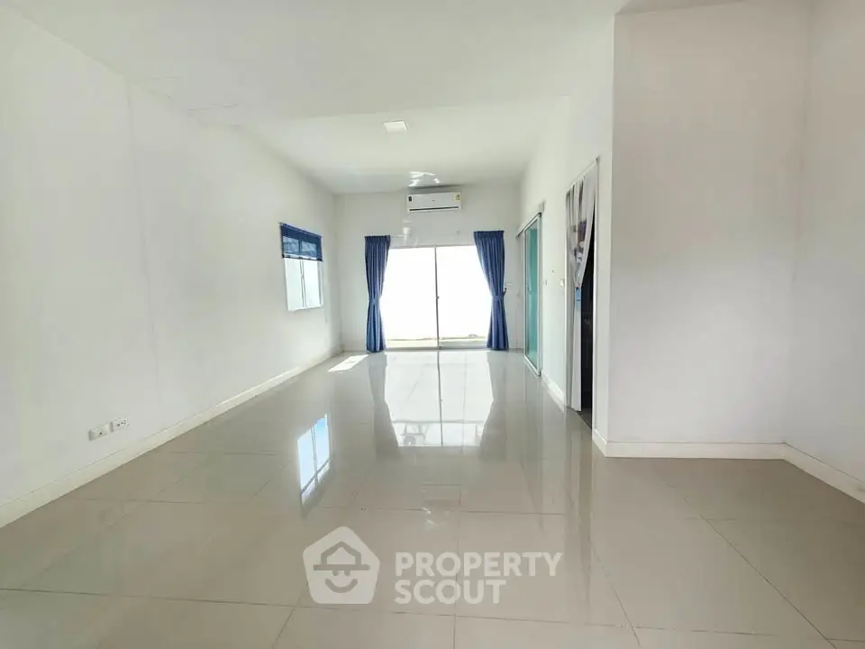 Spacious empty living room with glossy tiled floors and large windows for natural light.