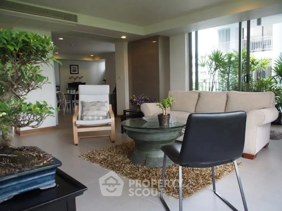 Spacious living room with modern furniture and large windows overlooking greenery.