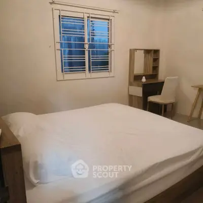 Cozy bedroom with minimalist decor and natural light from window.