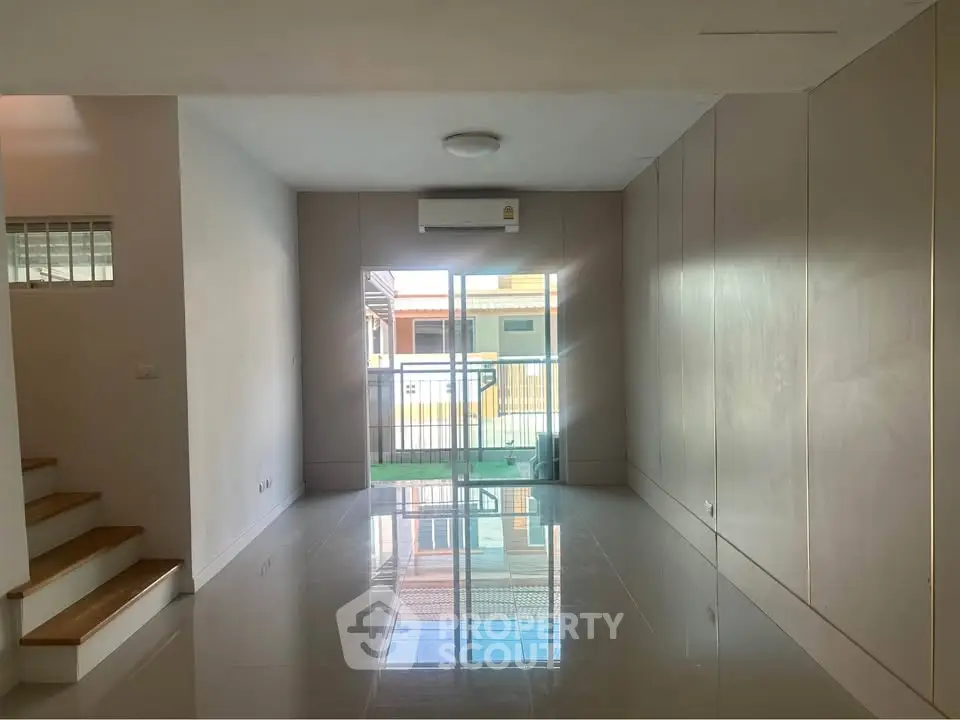 Spacious modern living room with glossy floors and large windows for natural light.