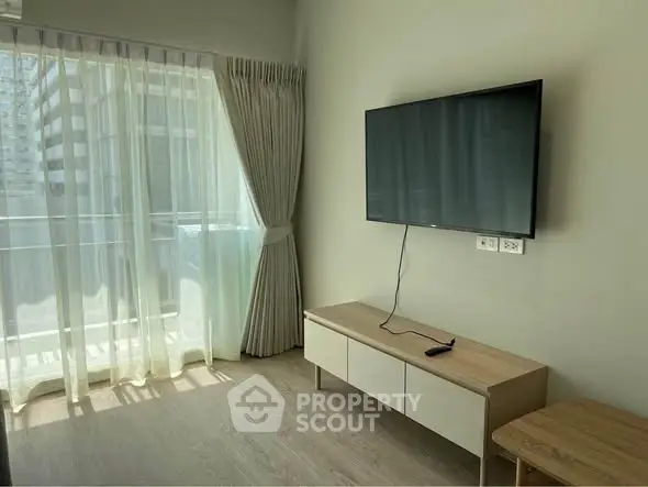 Modern living room with wall-mounted TV and large window for natural light.