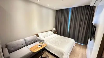 Cozy modern bedroom with a comfortable bed and stylish sofa, perfect for relaxation.