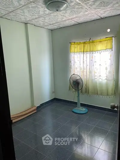 Cozy empty room with tiled floor and ceiling fan, perfect for customization.