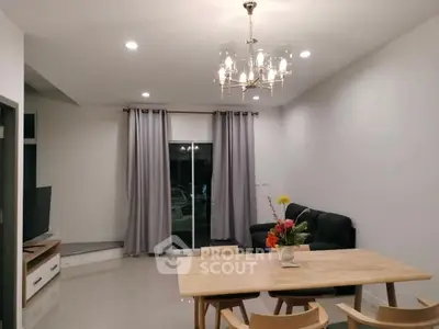 Modern living room with elegant chandelier and cozy seating area.