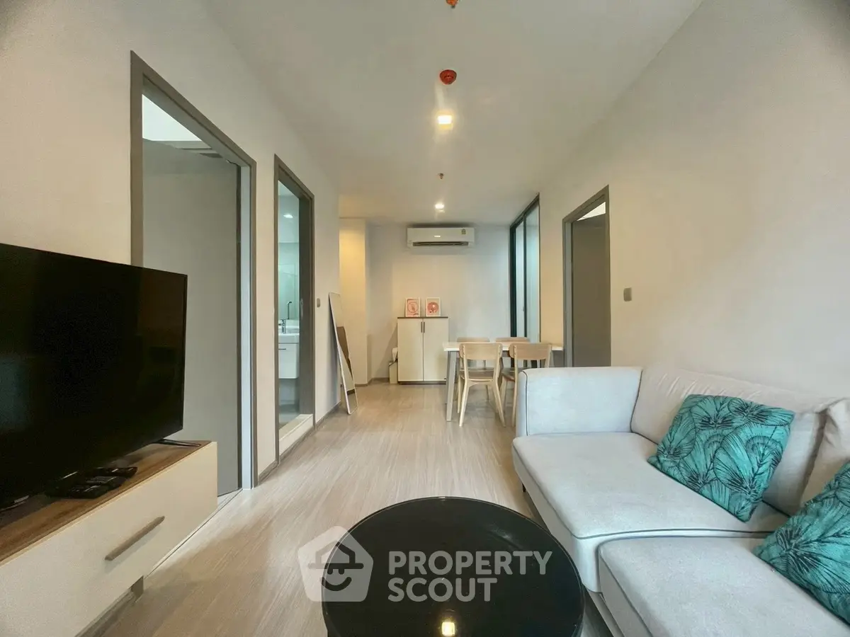 Modern living room with stylish decor and open layout, featuring a cozy sofa and sleek TV setup.