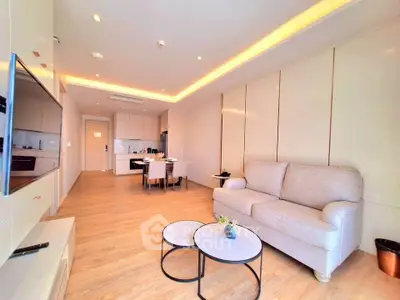 Modern living room with open kitchen, featuring sleek design and cozy furniture in a bright apartment.