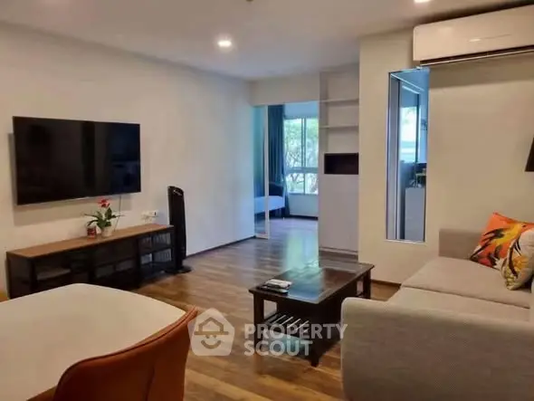 Modern living room with sleek design, featuring a wall-mounted TV, cozy sofa, and wooden flooring.