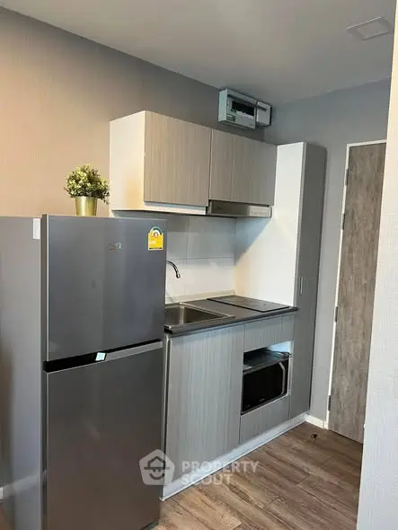 Modern compact kitchen with sleek cabinetry and stainless steel appliances in a stylish apartment.