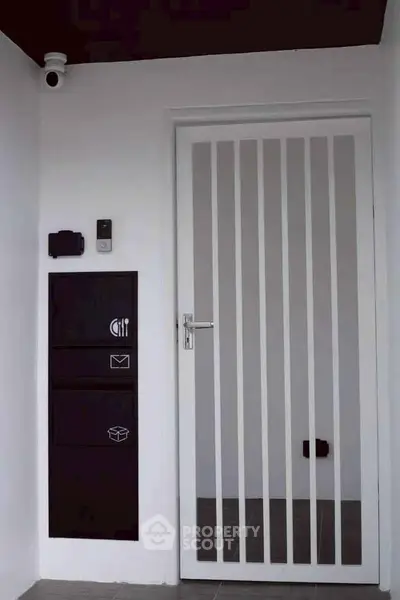 Modern entrance with sleek white door and security features