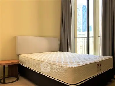 Modern bedroom with large window and city view, featuring a comfortable bed and stylish side table.
