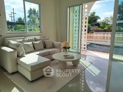 Bright living room with modern sofa and large windows overlooking garden.