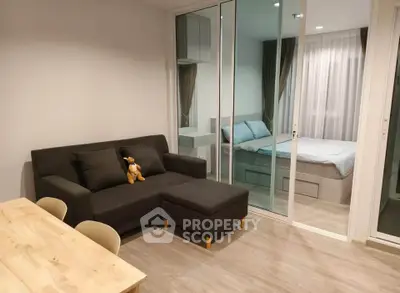Modern studio apartment with cozy living area and bedroom separated by glass doors.