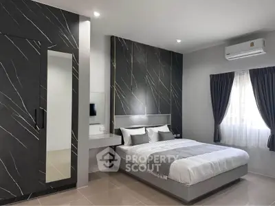 Modern bedroom with sleek design, featuring a stylish bed, built-in wardrobe, and air conditioning.