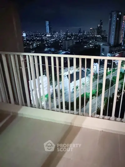 Stunning cityscape view from a high-rise balcony at night, showcasing urban skyline and vibrant lights.
