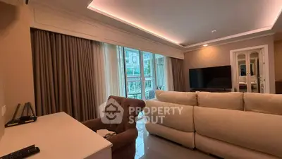 Spacious living room with elegant decor and large windows opening to a balcony.