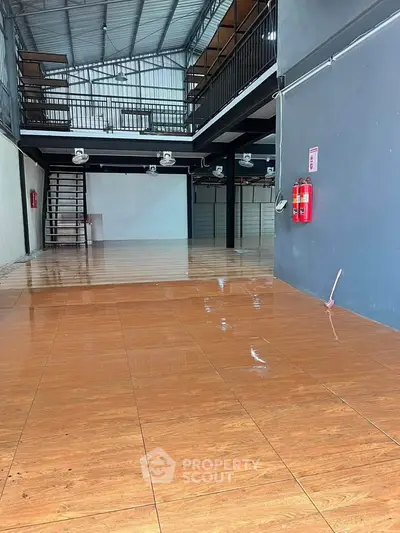 Spacious industrial-style commercial space with mezzanine and polished wooden floors.