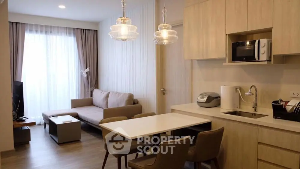 Modern living room with open kitchen, cozy sofa, and elegant lighting in a stylish apartment.