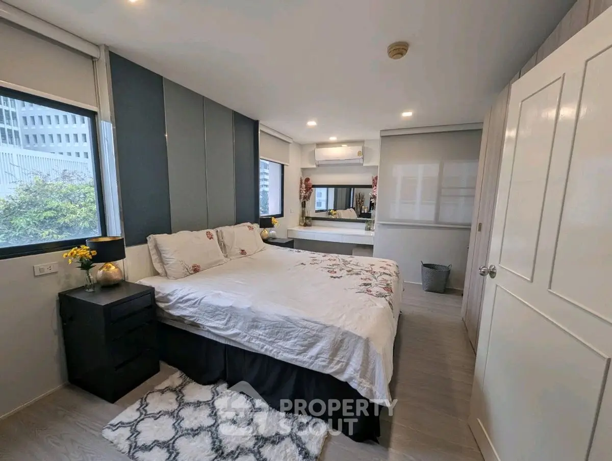 Modern bedroom with stylish decor and ample natural light in urban apartment.