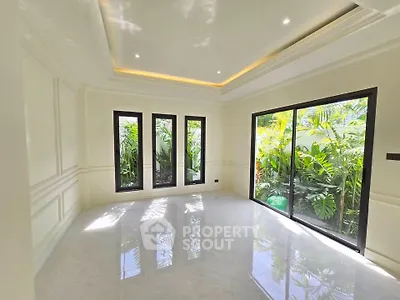 Spacious and bright living room with large windows and garden view, perfect for relaxation and entertaining.