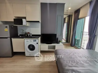 Modern studio apartment with compact kitchen and washing machine, featuring a balcony with city view.