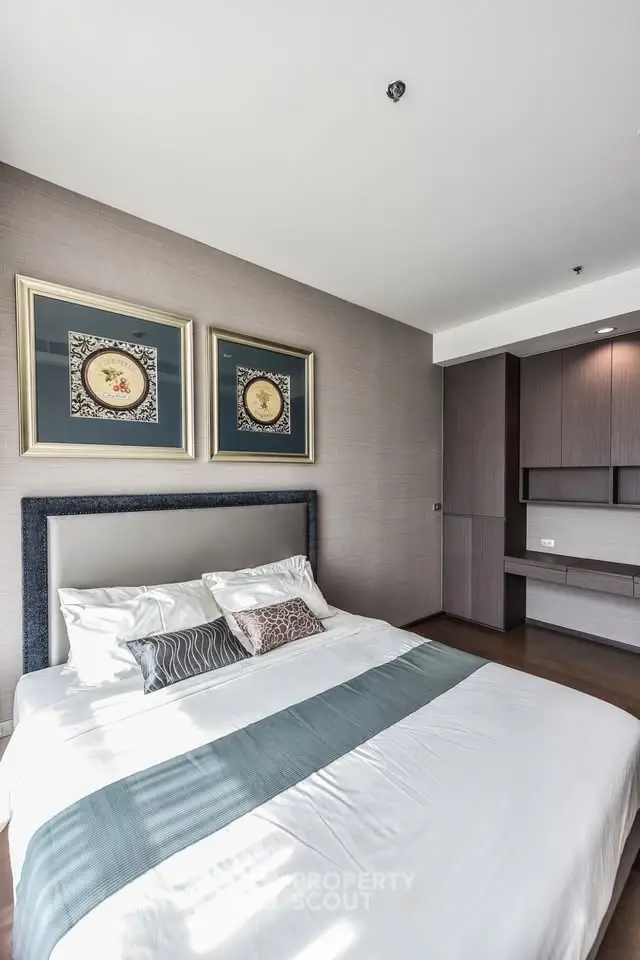 Modern bedroom with stylish decor and ample natural light, featuring elegant wall art and sleek built-in storage.