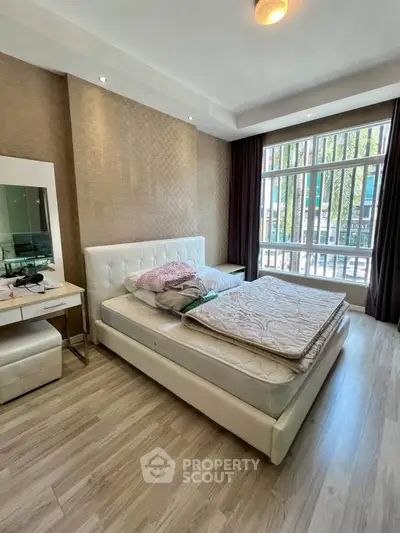Spacious bedroom with modern decor and large window offering natural light.