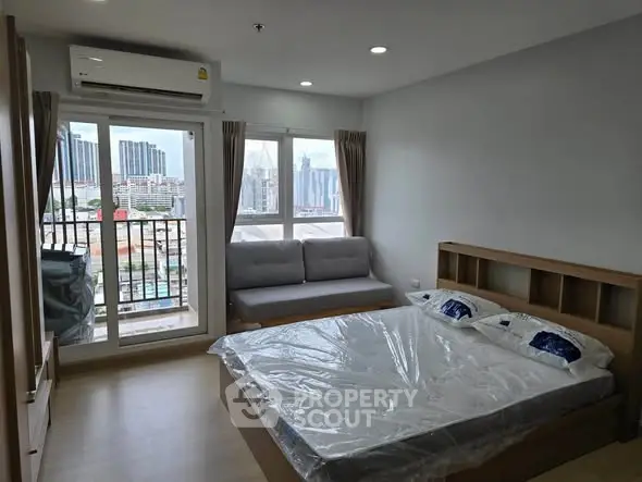 Modern bedroom with city view, featuring a cozy bed and balcony access in a high-rise apartment.