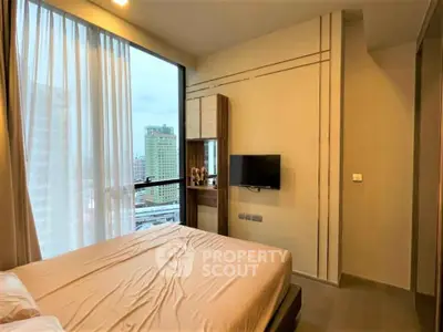 Modern bedroom with city view and wall-mounted TV in high-rise apartment.