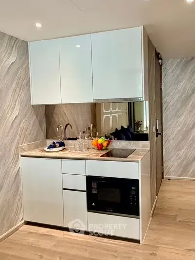 Modern compact kitchen with sleek cabinetry and built-in microwave, perfect for urban living.