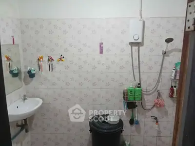 Functional bathroom with shower, sink, and water heater in a tiled setting.