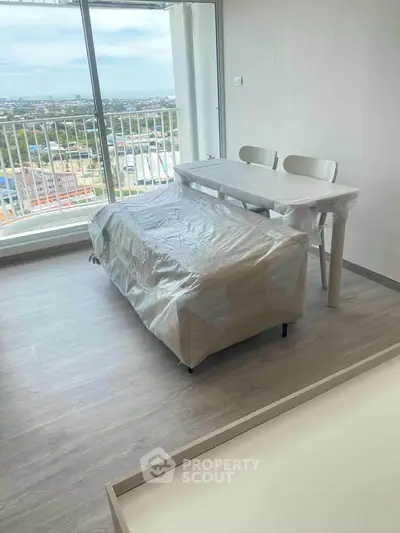 Modern living room with city view and covered furniture, perfect for urban living.