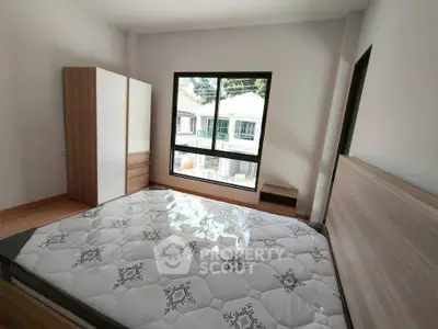 Spacious bedroom with large window and modern furniture in a bright home.