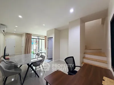 Modern open-plan living and dining area with elegant furniture and staircase