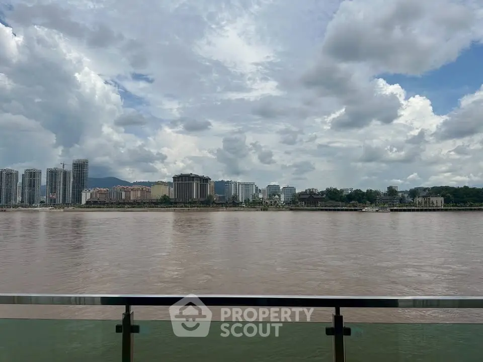 Stunning riverfront view with modern city skyline and cloudy sky, perfect for urban living enthusiasts.