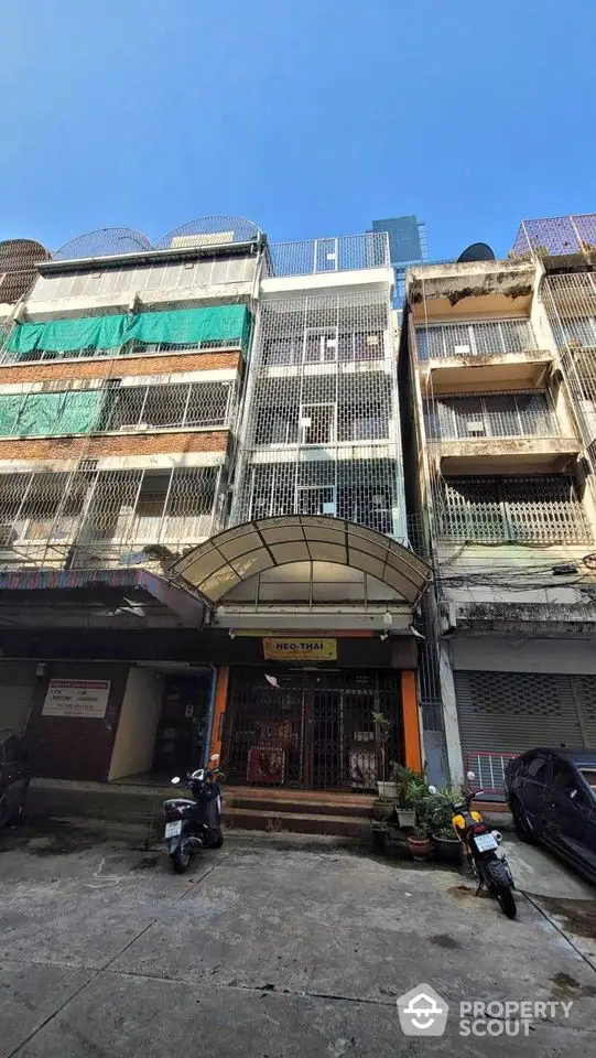 Multi-story urban building with gated entrance and parked motorcycles, showcasing city living.