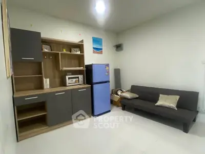 Modern living room with sleek furniture and compact kitchen appliances.