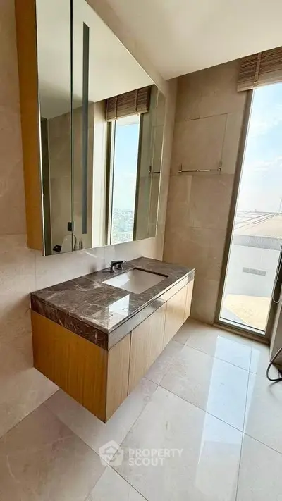 Luxurious bathroom with marble countertop and large window offering city views.